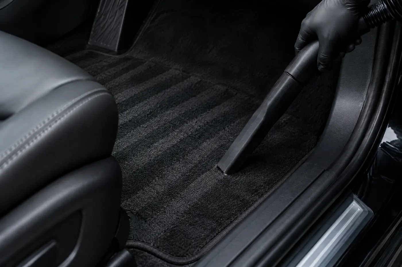 A vacuum nozzle leaving clean lines on a car floor mat